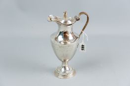 A George III silver jug having a circular base with a plain tapered body, shaped neck and string
