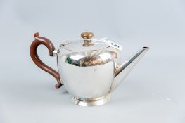 A plain circular silver teapot of slightly tapered form with straight spout, composition handle