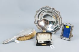 A small silver easel portrait frame; a cased silver pusher spoon, 0.5 ozs; an oval silver backed