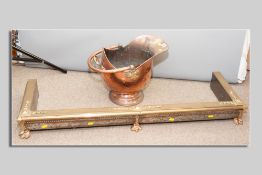 A copper helmet coal scuttle with swing handle, a brass and copper oblong fender on claw supports