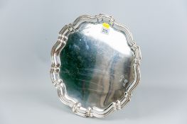 A circular silver tray, uninscribed and with stepped and shaped border, 13.5 ins (34 cms) diam, 34