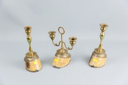A pair of brass candleholders and a double sconce candleholder each mounted on three horse's