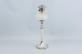 An octagonal based silver oil lamp, the base having a bead work and lined border to a panelled and
