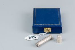 A cased silver cylindrical engine turned needle case, Birmingham 1968 and a silver thimble,