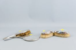 A pair of plain silver backed oval dressing table brushes, London 1934 and 1938 and a non-matching