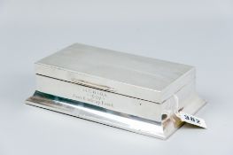 A large oblong engine turned silver cigarette box having a wider concave base and with golf