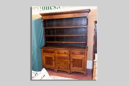 A 19th Century oak and mahogany Welsh dresser having a three shelf rack over a breakfront base