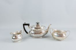 A three piece silver tea service, each piece of oval plain form, the inscribed teapot having a black