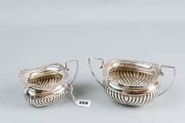 An oblong silver twin handled sugar basin of fluted and reeded form and with a matching milk jug,