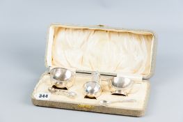 A cased three piece silver condiment set with spoons and the mustard pot with Bristol blue liner,