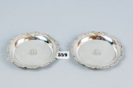 A pair of small sterling silver circular tray dishes by Tiffany having floral and scrolled