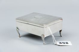 A small plain silver slightly oblong ring box with engine turned lid and on four corner supports,