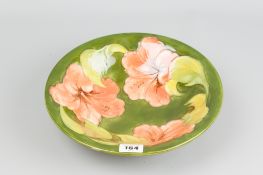 A Moorcroft pottery 'Hibiscus' green ground bowl, impressed painted marks to the base, 25.5 cms diam
