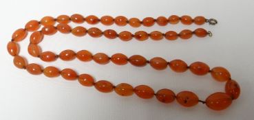 A necklace strand of 50 graduated red amber beads, 41cms long