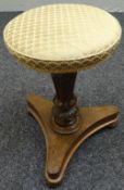 A revolving upholstered piano stool on a tripod base with carved support