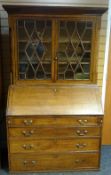 An oak bureau-bookcase, the base with four graduated drawers and hinged slope revealing a fitted