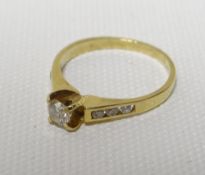 An 18ct yellow gold ring set with raised centre diamond and three diamonds to the shoulders