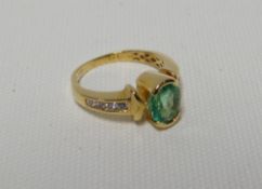An 18k yellow gold ring set with oval Colombian emerald, 1.71cts and with two rows of four