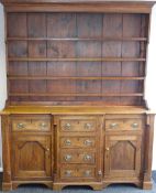 An early nineteenth century oak open-rack Welsh dresser having a break-front base with a bank of