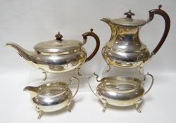 A four piece silver tea-set of oval plain form and on four feet with patterned borders and lignum