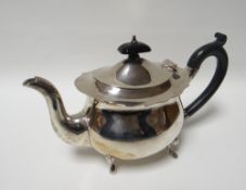 A silver oval teapot on four claw feet with crimped rim and ebonised handle and knop,  Birmingham