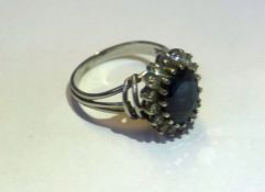 A sapphire and diamond cluster ring of oval form with sixteen outer diamonds in a white metal