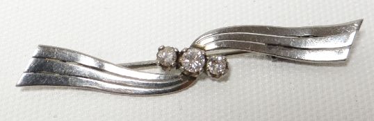 A three stone diamond bar brooch in unmarked white metal setting