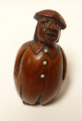 An early nineteenth century coquilla-nut carved novelty snuff-box in the form of  standing portly