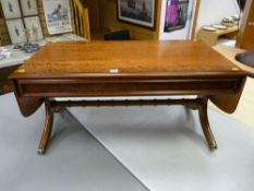A modern walnut effect twin flap coffee table with turned cross stretcher, splayed legs and brass