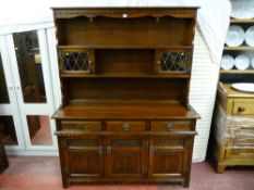 An Old Charm reproduction carved oak dresser with linenfold carved base cupboards, three frieze