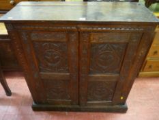 An early 20th Century carved oak two door standing cupboard, each door having twin inset panels with