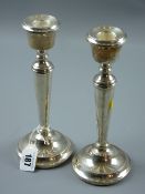 A pair of modern circular based silver table candlesticks having plain tapered columns, 21 cms high,