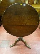A circular oak tilt top tripod table with turned centre column and gently curved supports, 76 cms