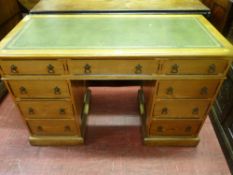 An Edwardian oak kneehole writing desk having a green tooled leather top and with a centre