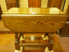 A reproduction oak swivel top twin flap side table on turned and block supports with cross