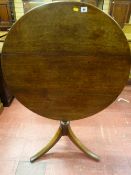 A circular oak tilt top tripod table with turned centre column and gently curved supports, 84 cms