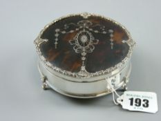 A circular silver ring box on three scrolled supports with fine silver and tortoiseshell lid