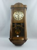 An early to mid 20th Century oak chiming wall clock with bevelled glass pendulum viewer, 86 cms