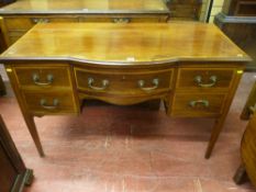 An Edwardian mahogany and crossbanded desk (former dressing table) with central bow drawer and two