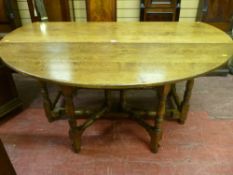 A substantial Cotswold made antique style oak drop leaf dining table with twin gate supports, of
