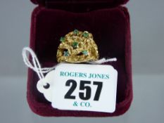 A heavy gold dress ring marked 750 with decorative shank and having six tiny emeralds in a