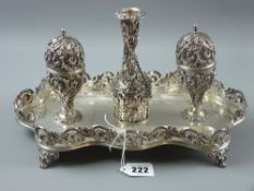 An oblong shaped silver inkstand having a floral and scrolled gallery on four scrolled supports