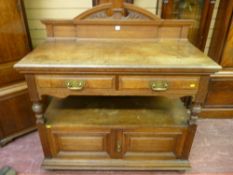 An Edwardian oak dumb waiter having two narrow top drawers to a centre shelf with two cupboards