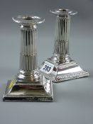 A pair of square based short stemmed Corinthian column silver candleholders having bead edge