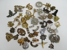 A quantity of assorted regimental cap badges, shoulder titles and collar badges