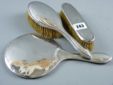 A silver backed hand mirror and two non-matching silver backed dressing table brushes
