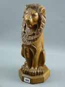 An early 20th Century nicely carved oak figure of a proudly sitting lion with feet to the fore on an