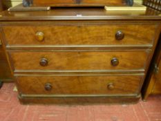 A Victorian mahogany round cornered chest of three drawers with turned wooden knobs on a plinth