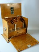 An early 20th Century oak stationery cabinet with lift-up lid and fall-down front opening to