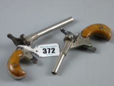 Two small rim fire pistols, white metal with walnut grips, stamped no. 76 and no. 50, 14 cms and